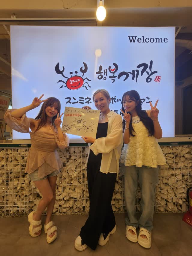 브랜드 로고가 띄워진 Welcome 스크린 앞에서 손으로 쓴 메시지 보드를 든 손님들