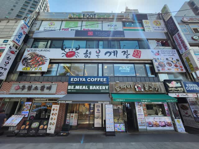 순미네행복게장 동대문점 외관 — 2층에 붉은 게 그림과 ‘행복게장’ 간판이 걸린 건물, 1층에는 커피숍과 베이커리